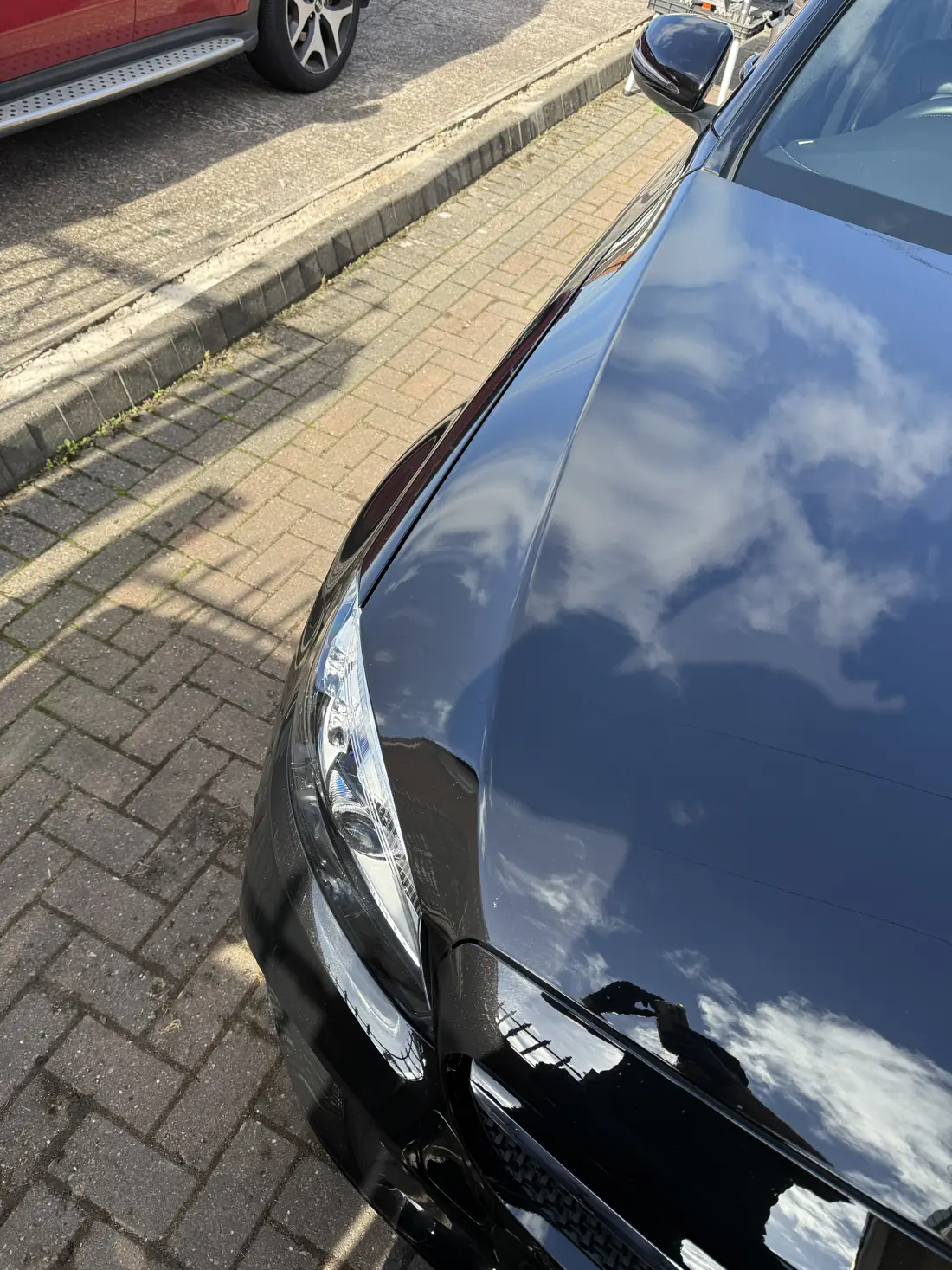 Black car door and wing reflecting the sky after machine polishing