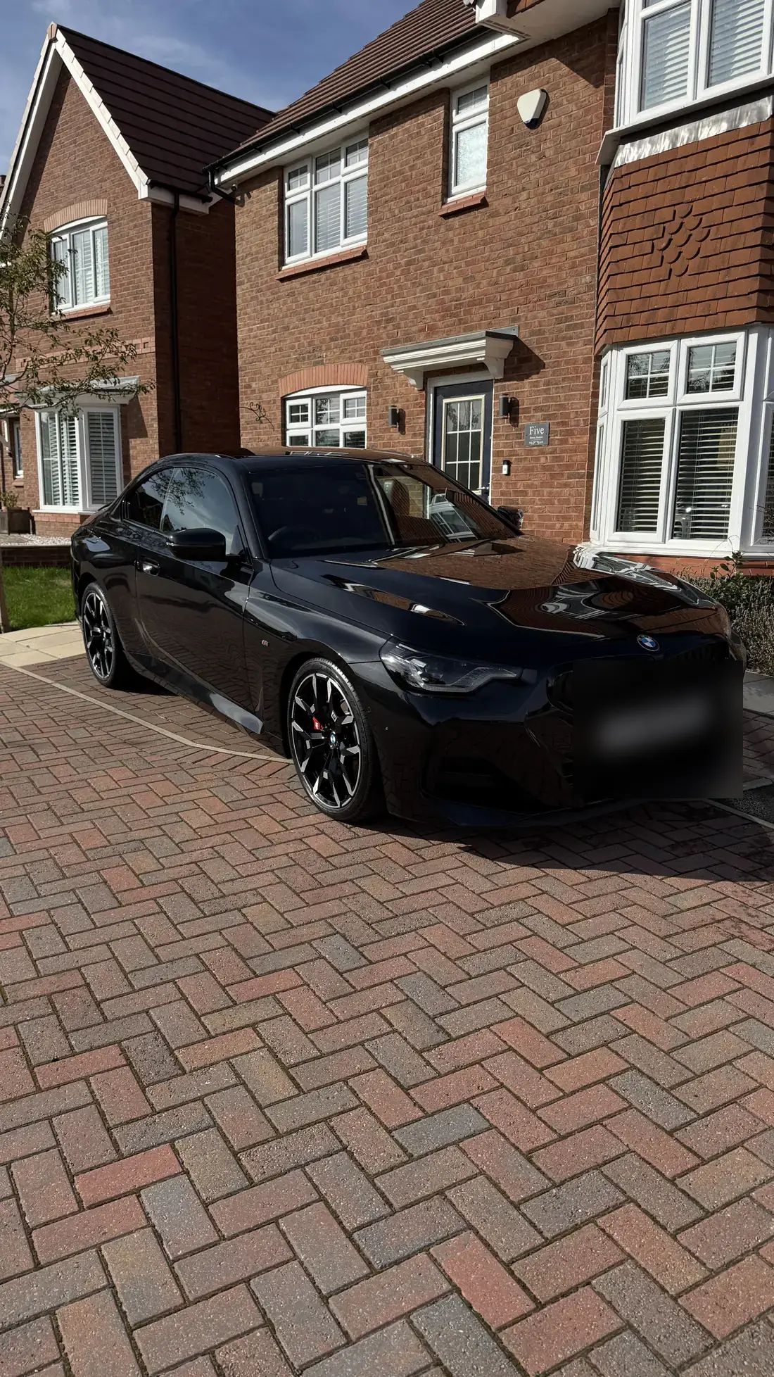 Black BMW coupe on a block-paved drive