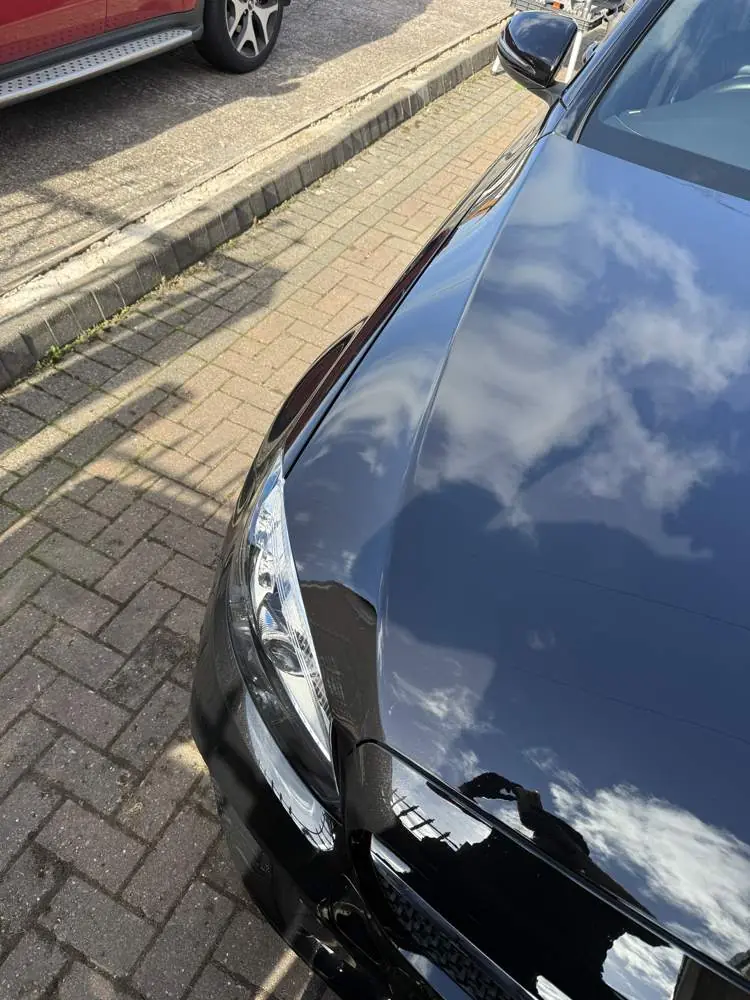Black Mercedes bonnet after machine polishing, reflecting the clouds